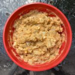 Potato salad in a red bowl on a glass table