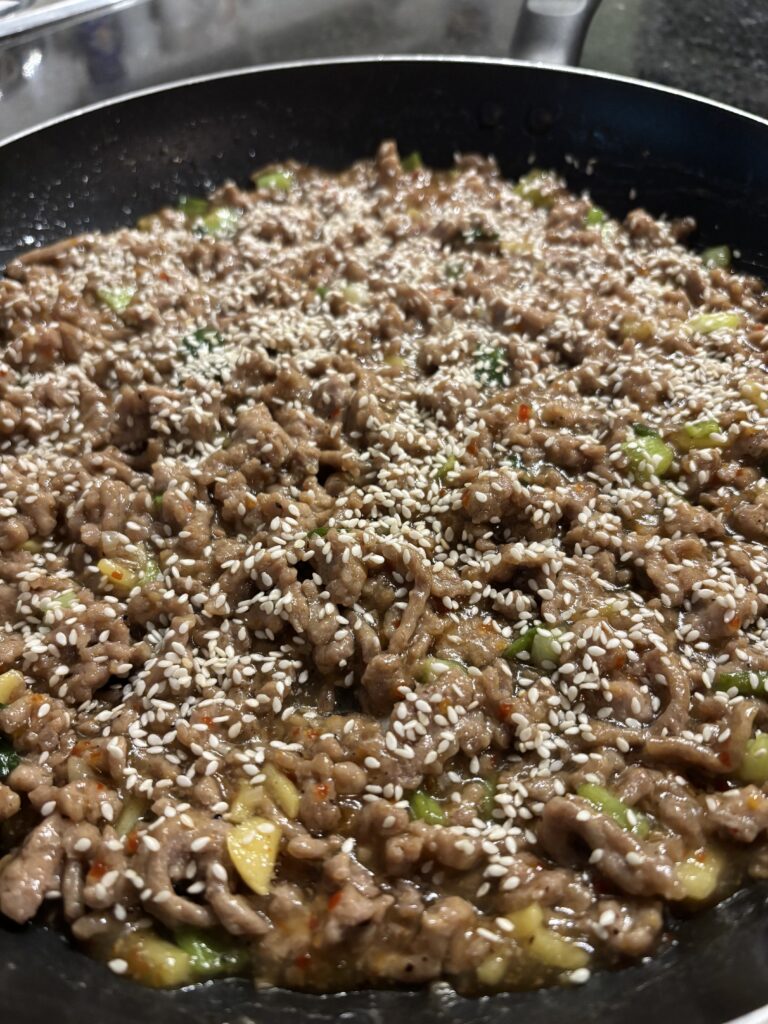 A closeup of sweet chili chicken in a skillet on a black countertop