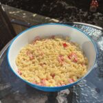 Macaroni salad in a blue bowl on a glass outdoor table