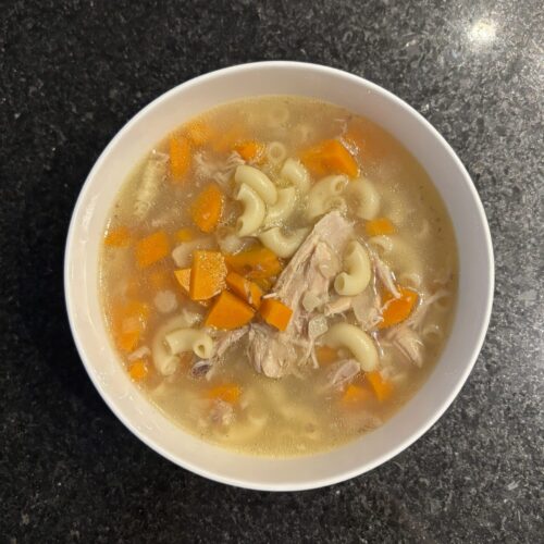 Chicken soup on a beige bowl on a black countertop