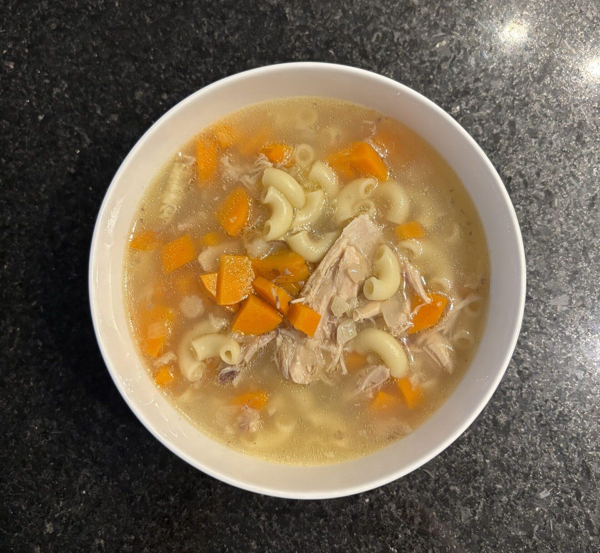 Chicken soup on a beige bowl on a black countertop